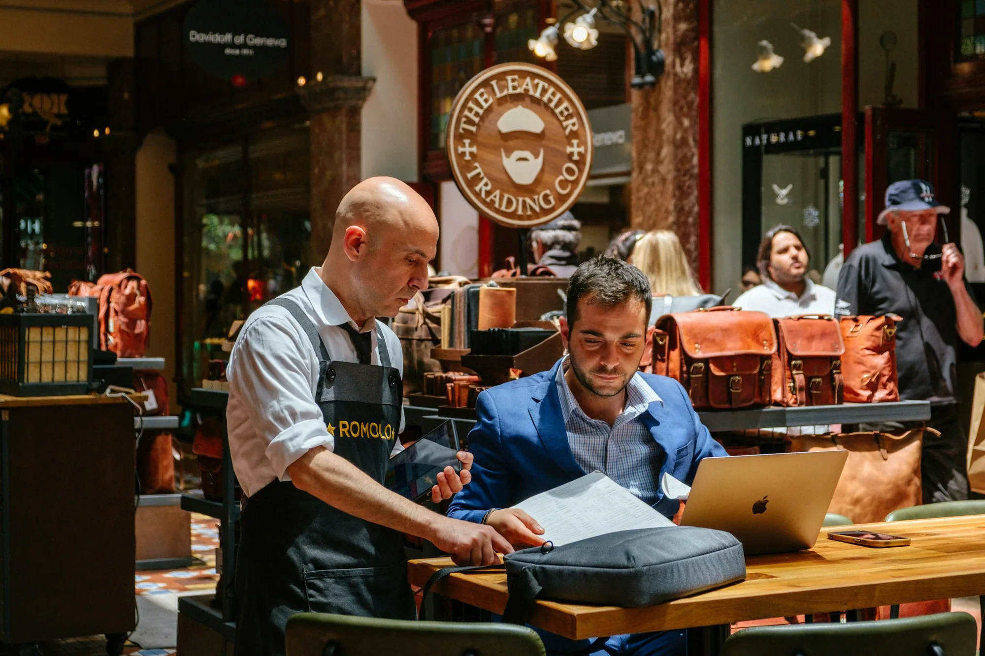 A shop owner and advisor reviewing records together at a counter.